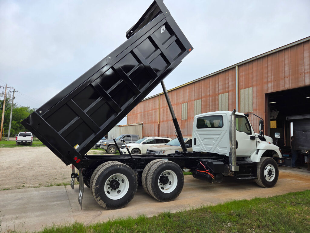 Custom dump truck on an International chassis with the black Warren dump body fully raised