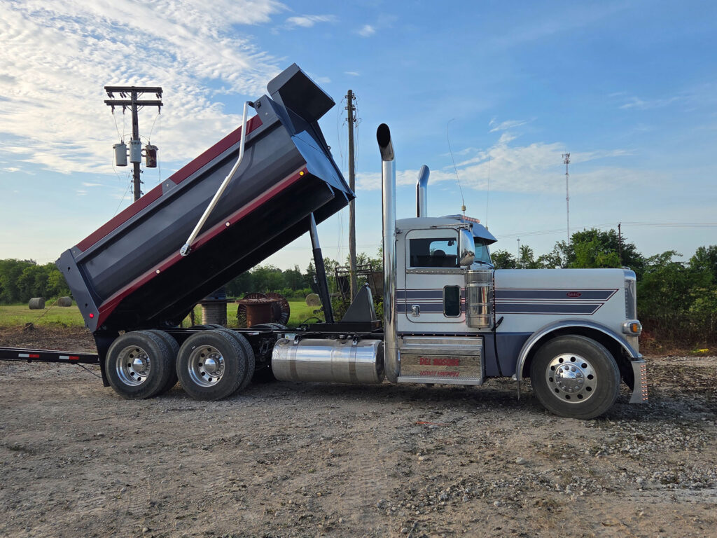 Side view of the Del Bosque Peterbilt truck and pup with the Warren WS-700 15 foot dump bed raised and variable cab shield between the stacks