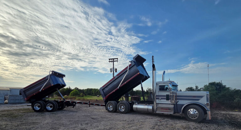 Peterbilt dump truck and pup combo with both Warren WS-700 dump beds raised in the dump position under a Texas sky
